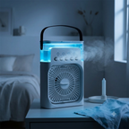 A portable electric fan and humidifier combo device with a handle, shown glowing with blue LED lights in a bedroom setting. Steam is visibly emitting from the top, with a bed and window in the background.