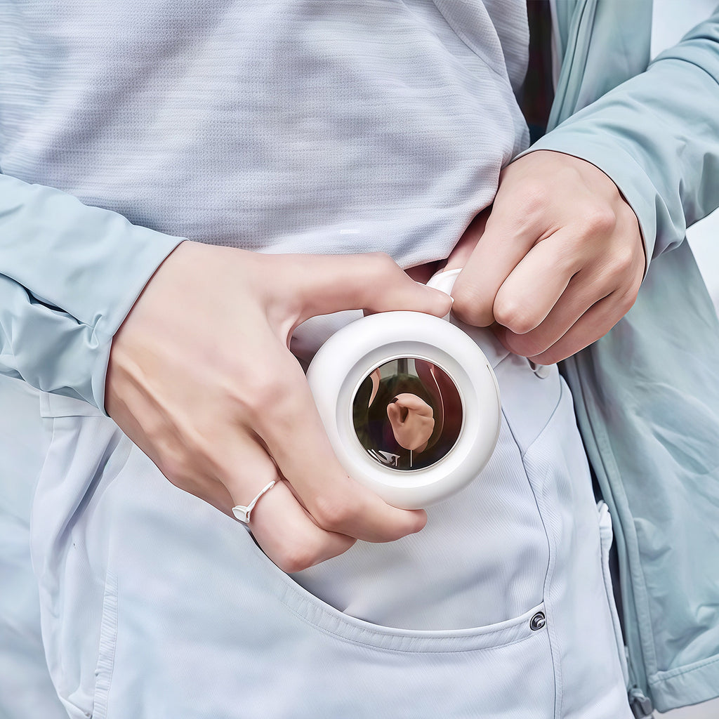 Person holding a white round device with a mirror, wearing a light blue jacket.